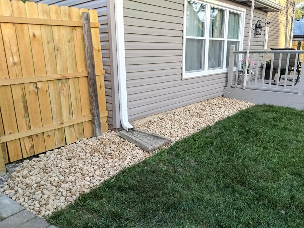 Decorative gravel bed installed along the side of a house next to a fence